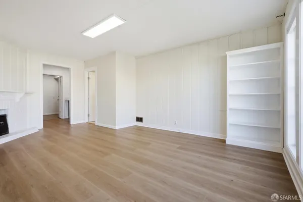 a view of an empty room with a window and wooden floor