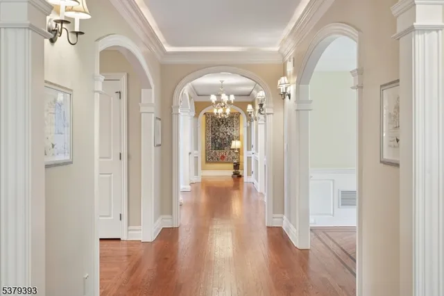 a view of a hallway with wooden floor and chandelier