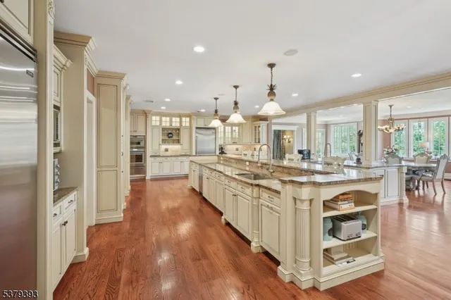 a large kitchen with stainless steel appliances a large counter top a stove and a wooden floors