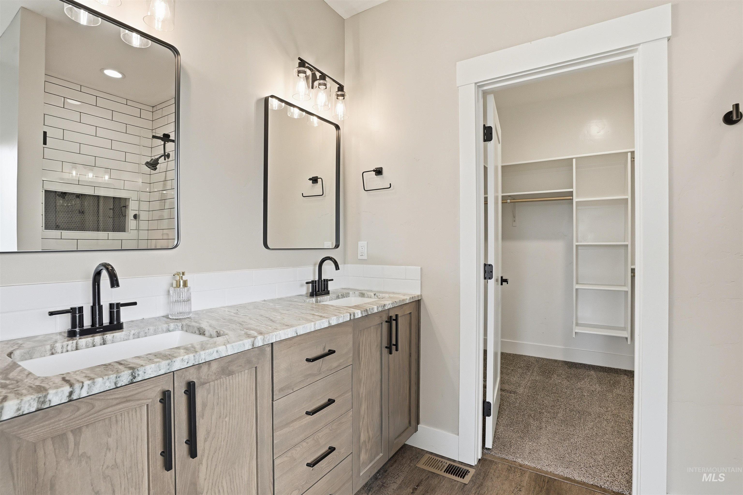 6617 Red Rock Road Marsing, ID 83639 - Photo 15 of 39 Bathroom with double vanity, a walk in closet, dark wood-style flooring, tiled shower, and dark colored carpet