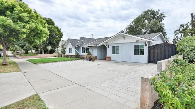a view of a white house with a small yard and large trees