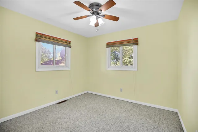 an empty room with a window and a fan