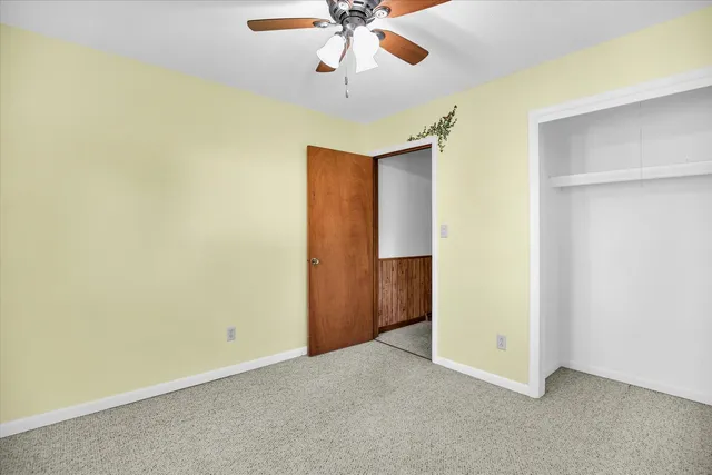 an empty room with a ceiling fan and carpet