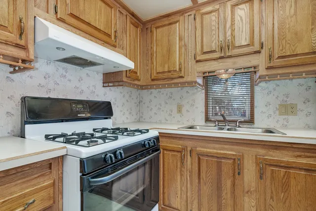 a kitchen with stainless steel appliances granite countertop a stove a sink and a microwave