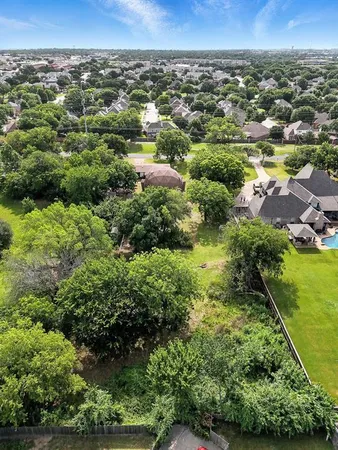 an aerial view of a residential houses with outdoor space and trees
