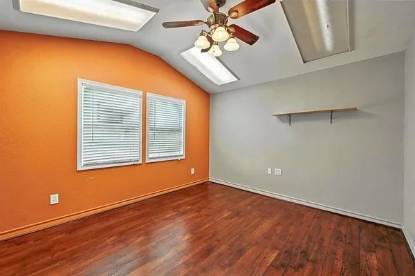 a view of an empty room with window and wooden floor