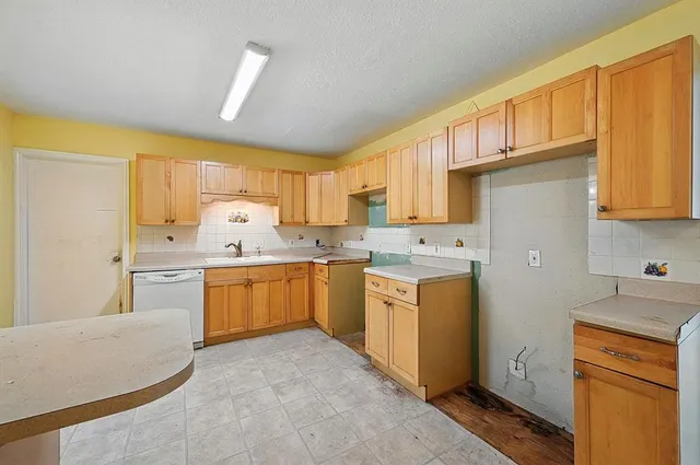 a kitchen with a sink a stove a refrigerator cabinets and a window