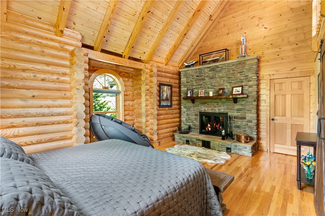 1784 North Medina Line Road Akron, OH 44333 - Photo 14 of 50 Bedroom with high vaulted ceiling, a wooden ceiling with exposed beams, wood finished floors, a fireplace, and log walls