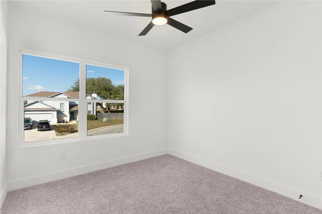 an empty room with a window and a fan
