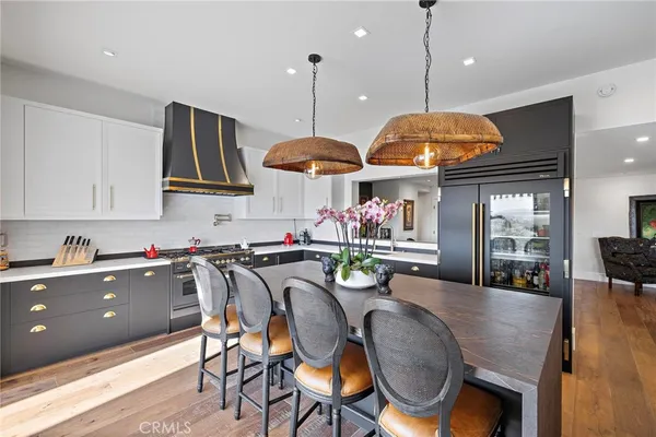 a kitchen with stainless steel appliances granite countertop a stove a sink a dining table and chairs with wooden floor