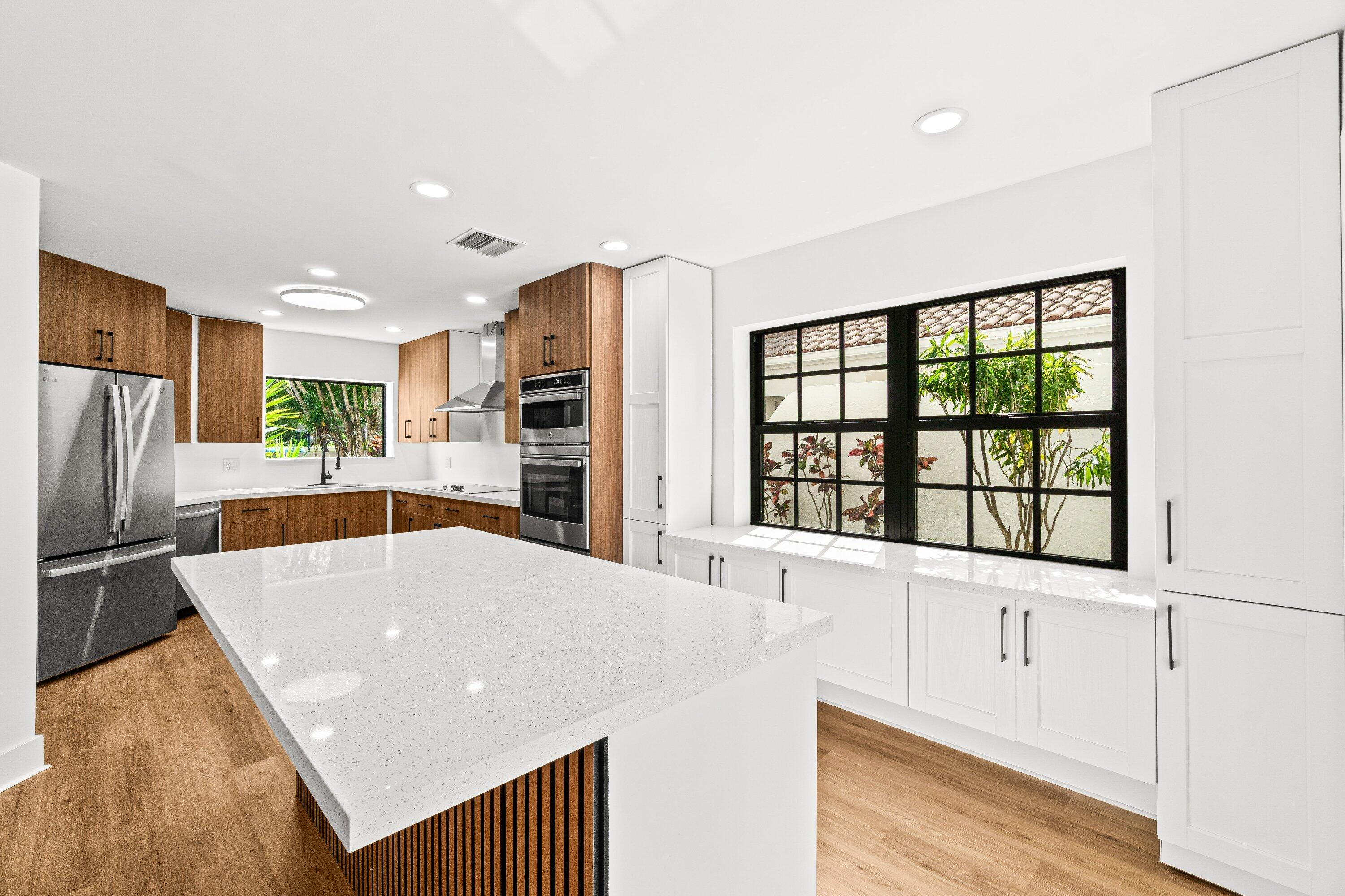 22548 Caravelle Circle, Unit 22548 Boca Raton, FL 33433 - Photo 14 of 40 a kitchen with stainless steel appliances kitchen island granite countertop a refrigerator a stove and a wooden cabinets with wooden floor