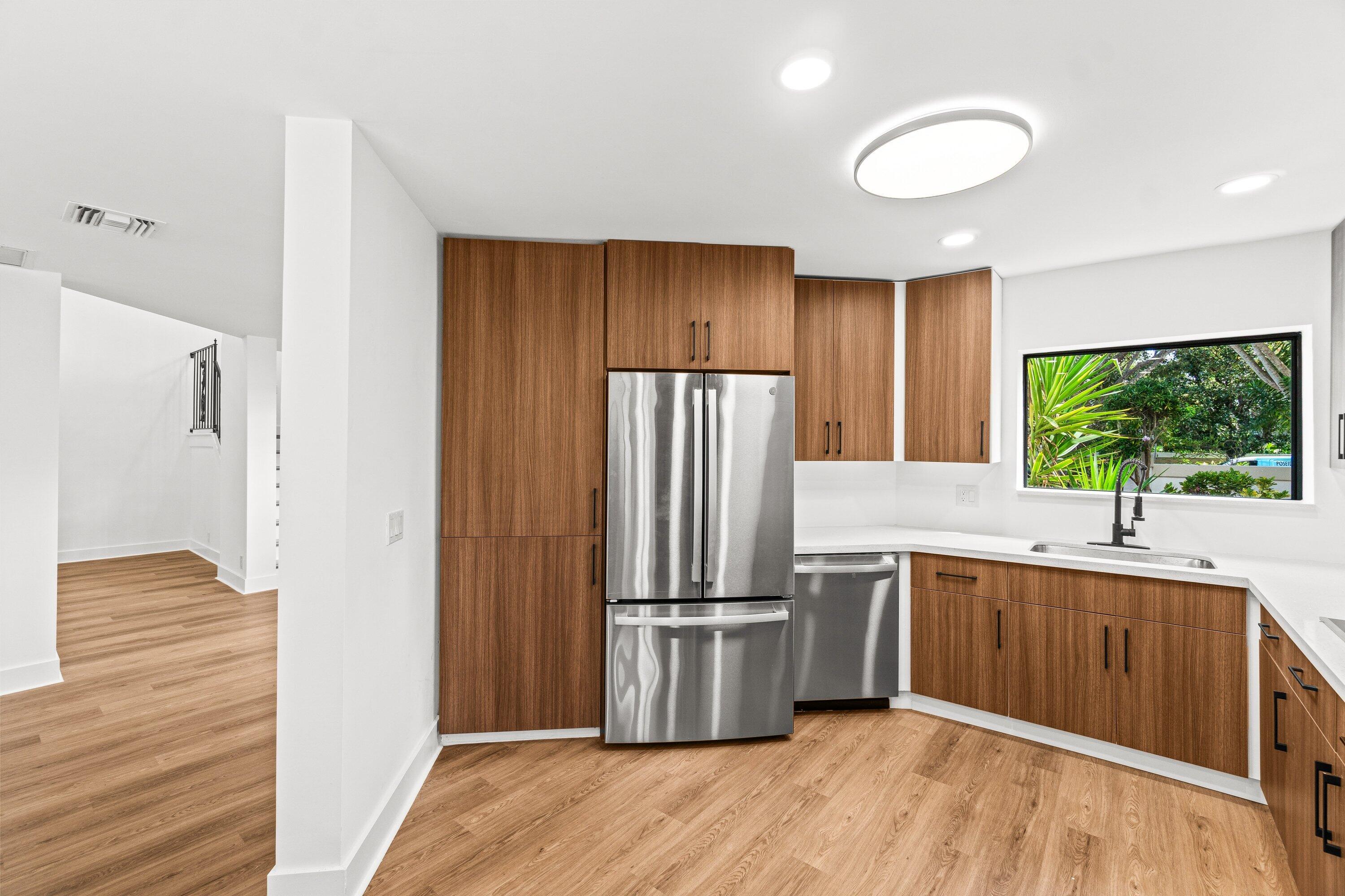 22548 Caravelle Circle, Unit 22548 Boca Raton, FL 33433 - Photo 18 of 40 a kitchen with stainless steel appliances granite countertop a refrigerator a sink dishwasher and wooden cabinets with wooden floor
