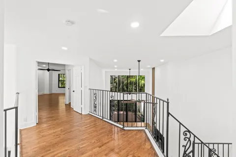 an empty room with wooden floor ceiling fan and windows