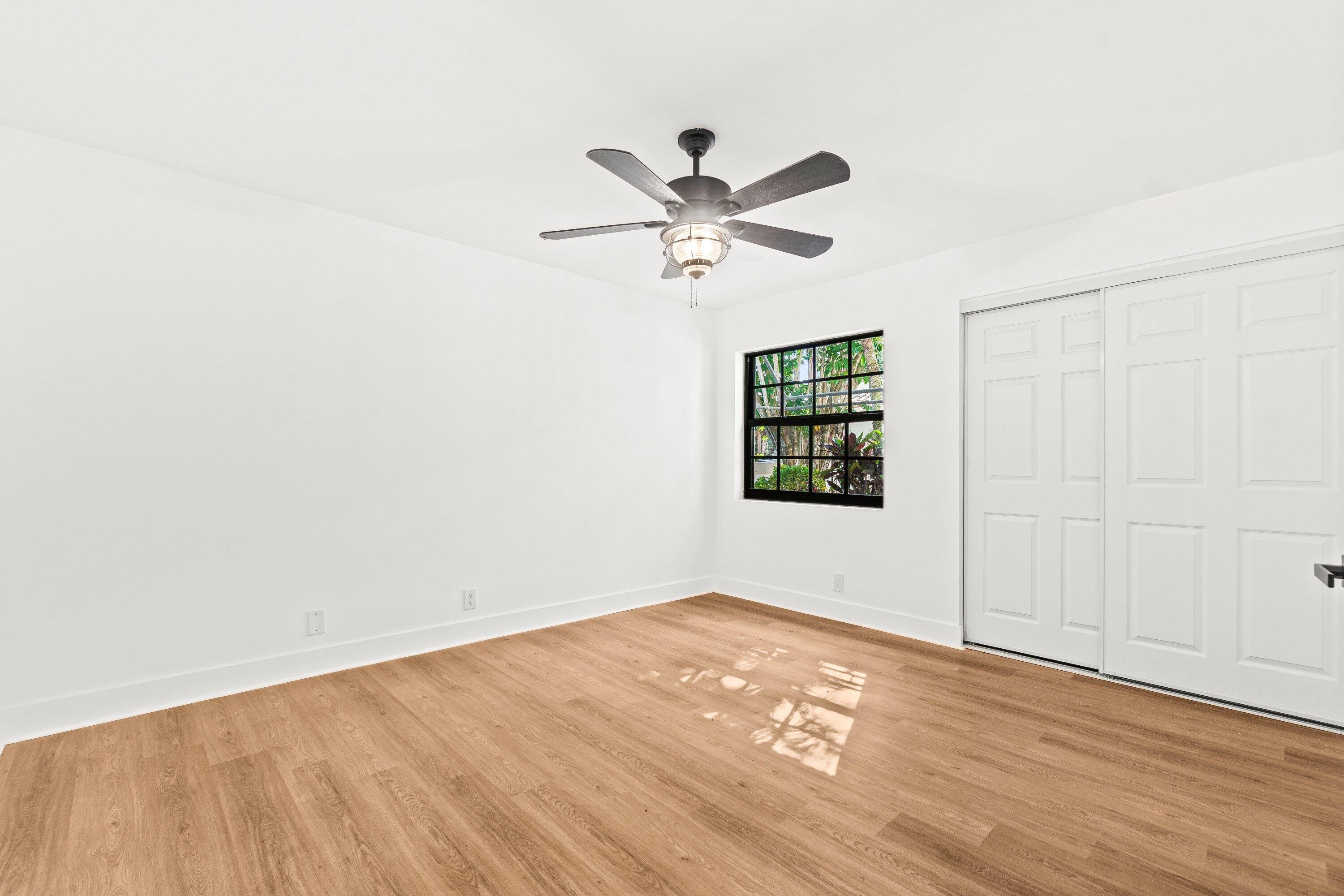 22548 Caravelle Circle, Unit 22548 Boca Raton, FL 33433 - Photo 22 of 40 an empty room with wooden floor ceiling fan and windows