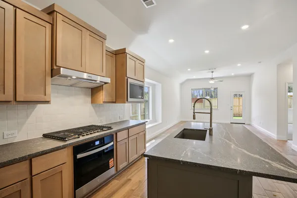 an empty room with wooden floor and a ceiling fan