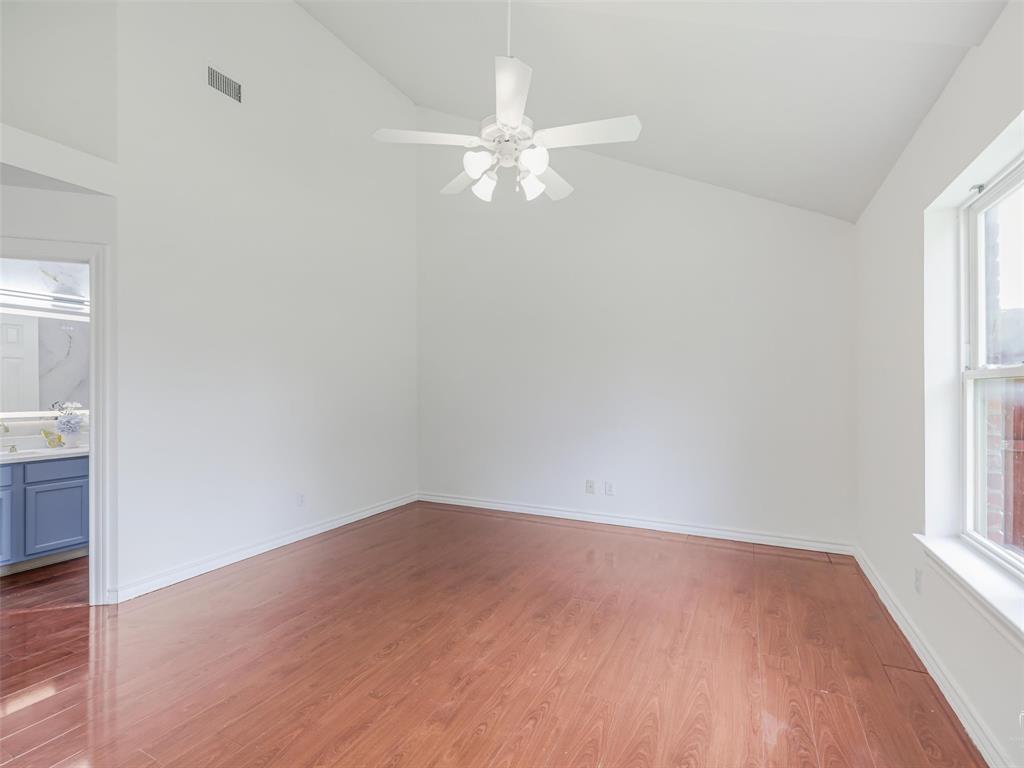1716 East Parker Road Plano, TX 75074 - Photo 19 of 25 Spacious primary room featuring vaulted ceilings, wood-finish flooring, a ceiling fan, and a single window