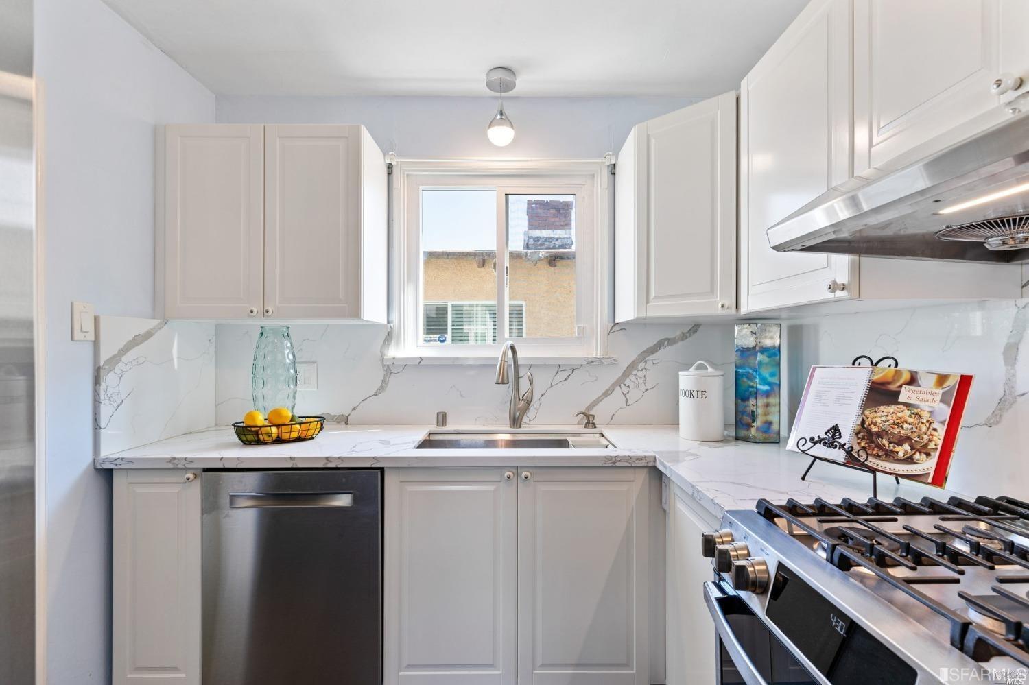 a kitchen with stainless steel appliances a stove a sink cabinets and a window