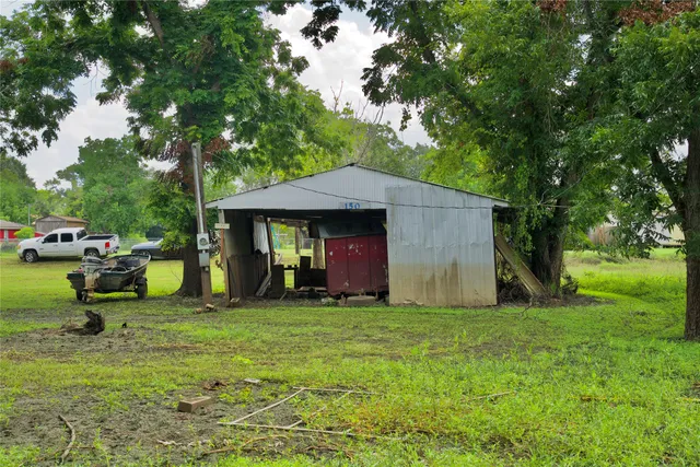 a view of a fire pit in front of a big yard with large trees