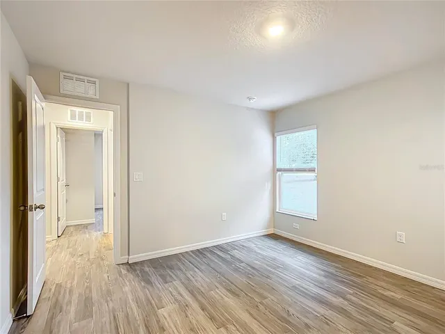 an empty room with wooden floor and windows