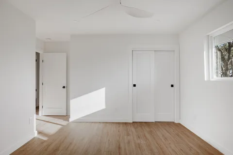 a view of an empty room with wooden floor and a window