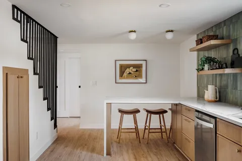 a kitchen with stainless steel appliances granite countertop a table chairs and a wooden floor