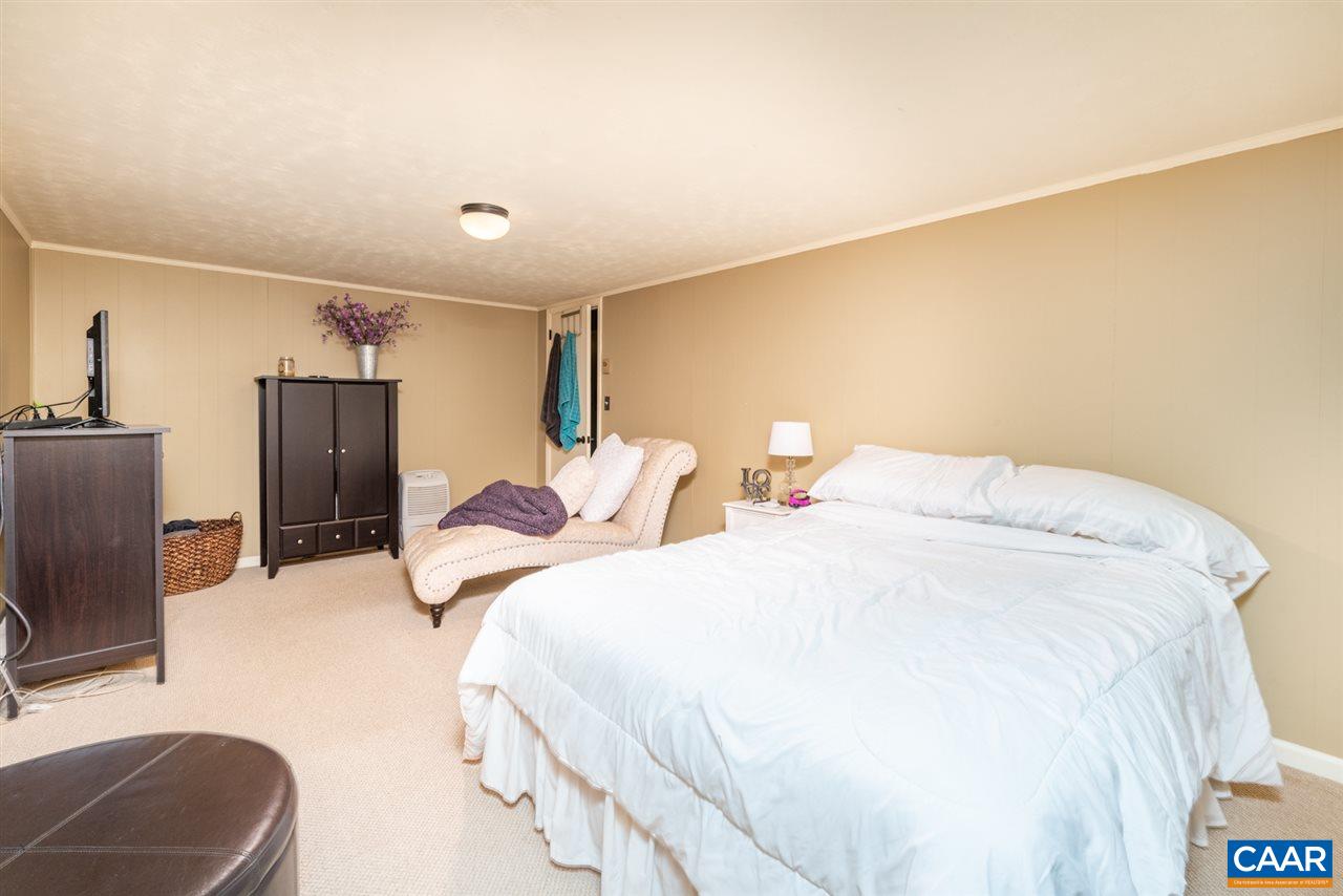 2564 Stagebridge Road Lovingston, VA 22949 - Photo 31 of 47 a bedroom with a bed a couch and a flat screen tv