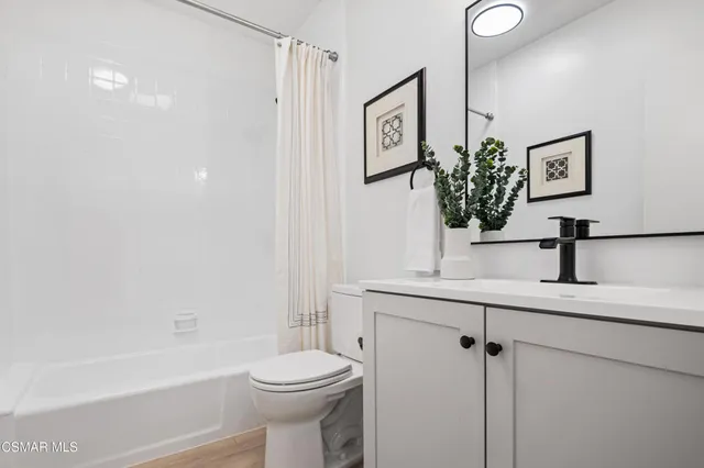 a bathroom with a sink a toilet a mirror and shower