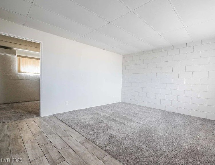 239 West Cleveland Avenue, Unit 1 Las Vegas, NV 89102 - Photo 2 of 12 Empty room with light wood-type flooring, light carpet, a wall mounted air conditioner, and concrete block wall