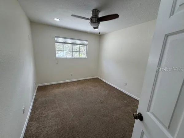 an empty room with a ceiling fan and window