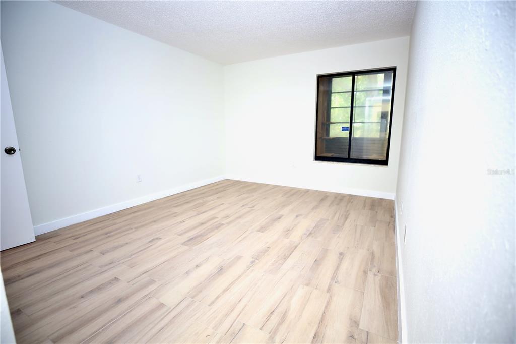 11702 Raintree Village Boulevard, Unit B Temple Terrace, FL 33617 - Photo 17 of 38 an empty room with wooden floor and windows