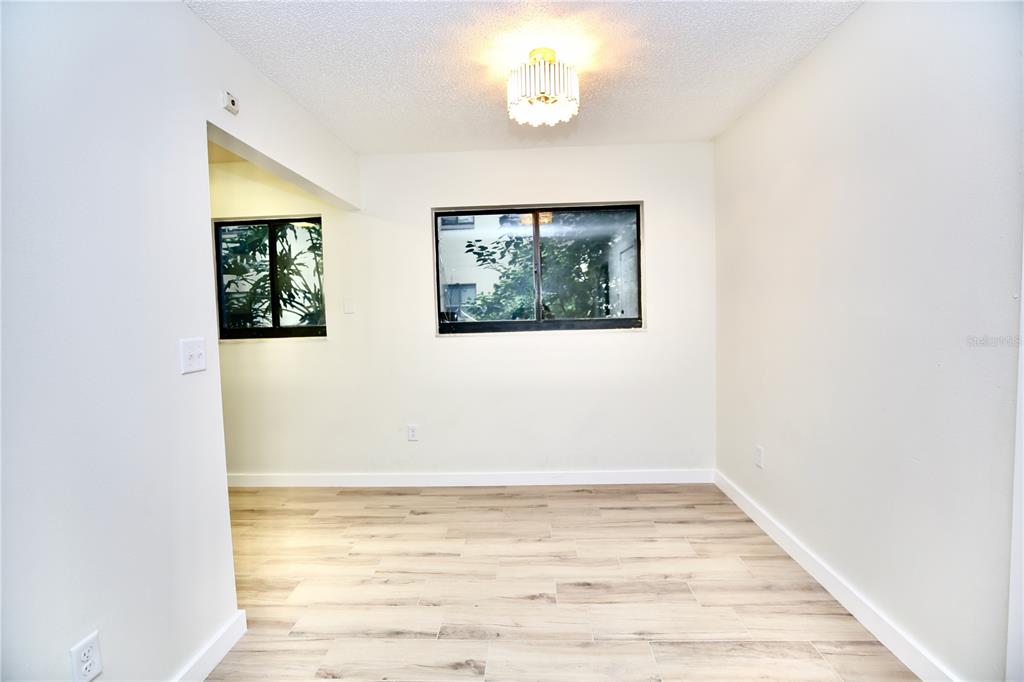 11702 Raintree Village Boulevard, Unit B Temple Terrace, FL 33617 - Photo 3 of 38 an empty room with wooden floor chandelier fan and windows