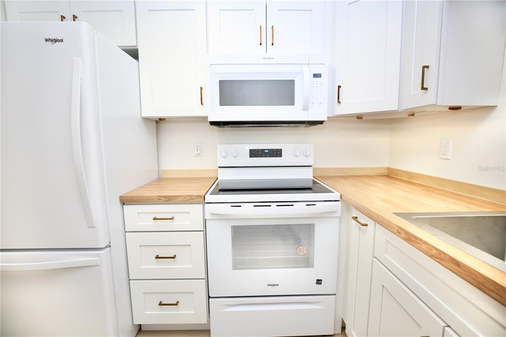 11702 Raintree Village Boulevard, Unit B Temple Terrace, FL 33617 - Photo 6 of 38 a kitchen with granite countertop white cabinets and white appliances