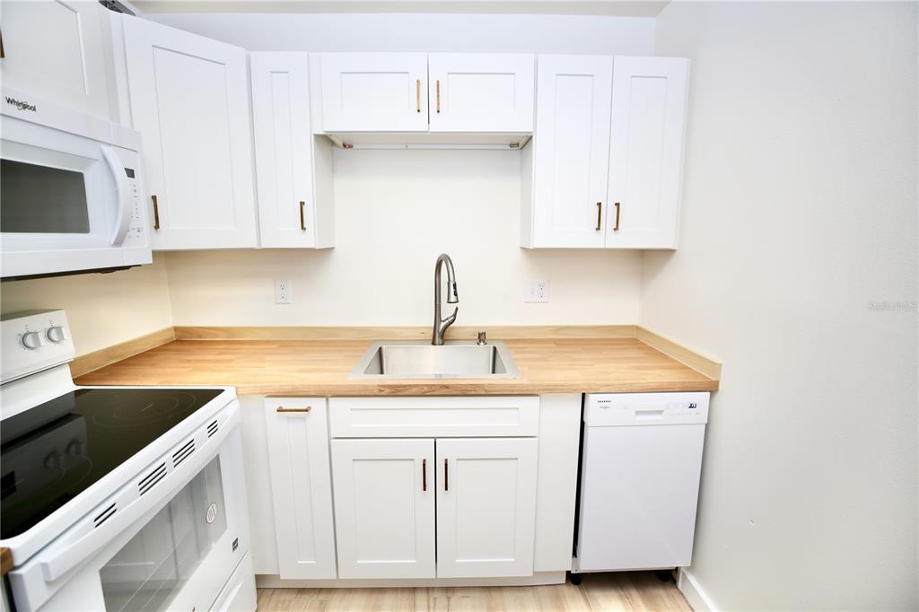 11702 Raintree Village Boulevard, Unit B Temple Terrace, FL 33617 - Photo 7 of 38 a kitchen with white cabinets sink and white appliances