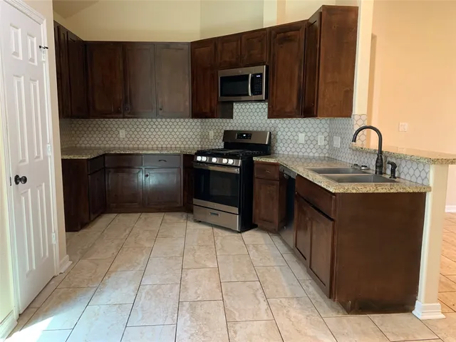 a kitchen with stainless steel appliances granite countertop a stove a sink and a microwave