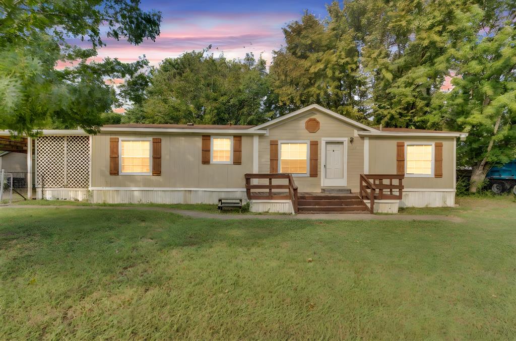 a front view of a house with a garden and trees