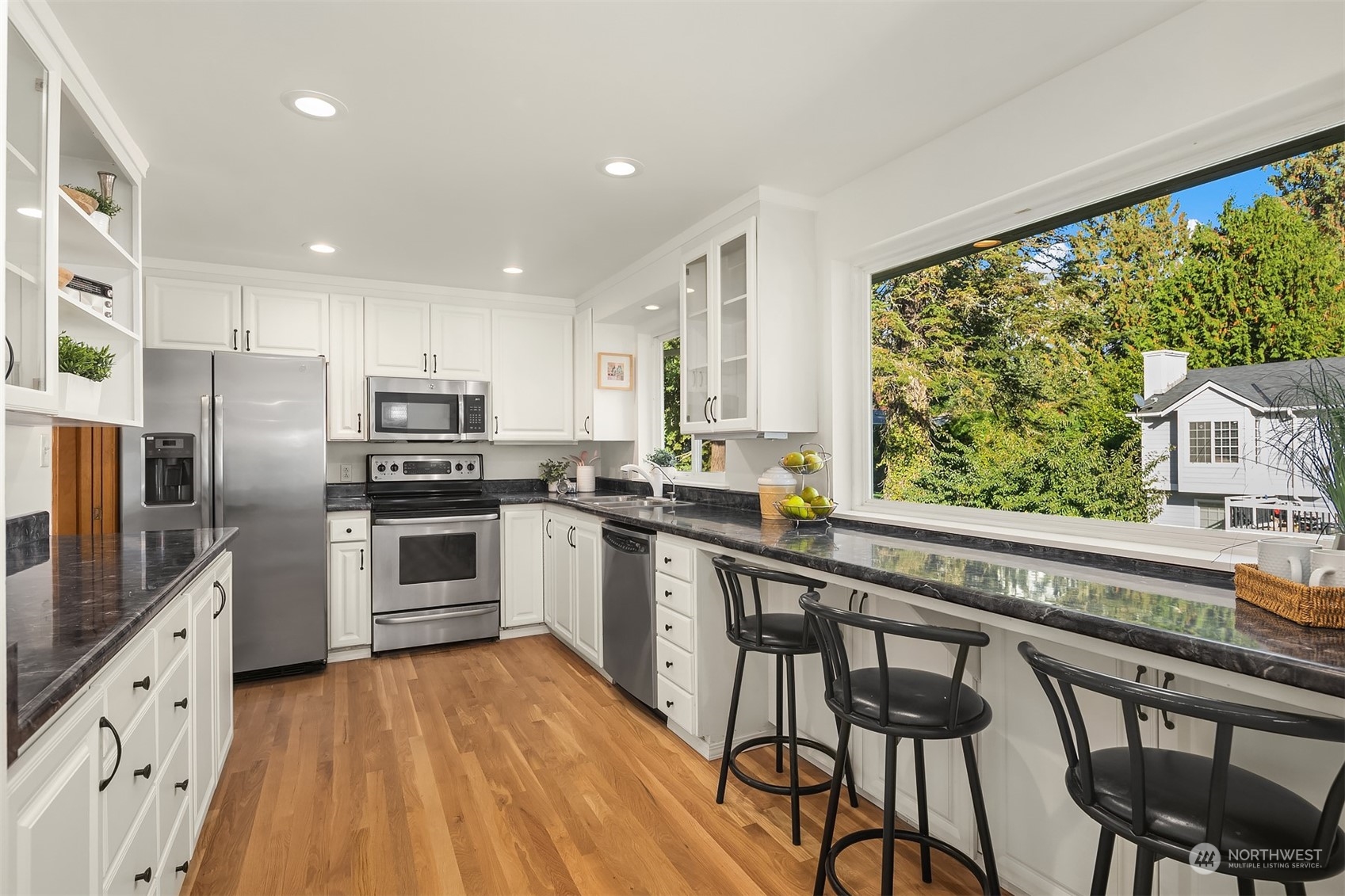 1834 North 183rd Street Shoreline, WA 98133 - Photo 14 of 40 a kitchen with granite countertop a stove a sink dishwasher a refrigerator with a dining table and chairs with wooden floor