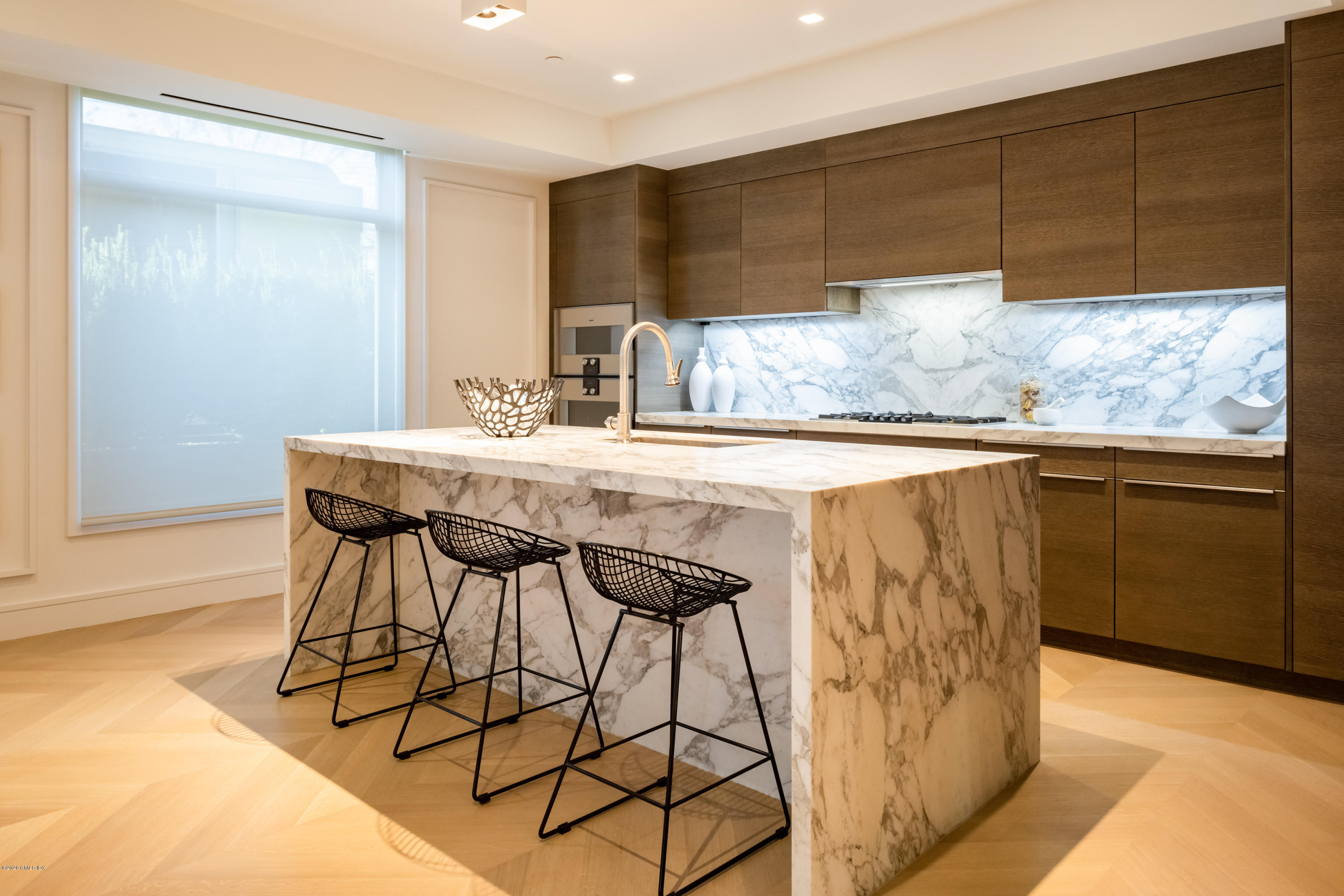 125 Field Point Road, Unit 1A Greenwich, CT 06830 - Photo 3 of 25 a kitchen with stainless steel appliances kitchen island granite countertop a table chairs in it and wooden floors