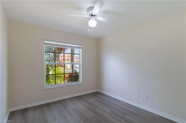 an empty room with windows and ceiling fan