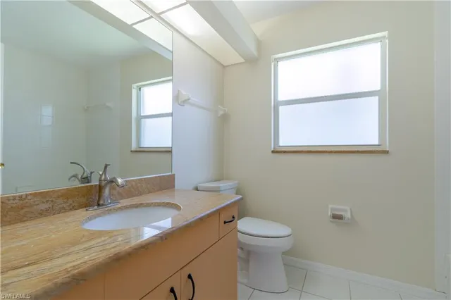 a bathroom with a granite countertop sink a toilet and a window