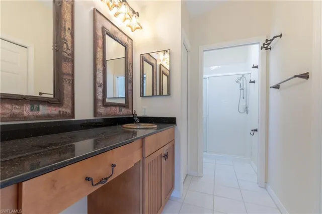 a bathroom with a granite countertop sink a mirror and a shower