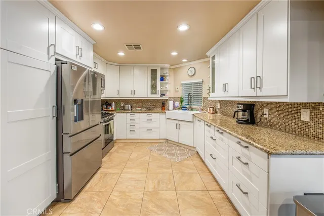 a large kitchen with stainless steel appliances granite countertop a refrigerator sink and cabinets