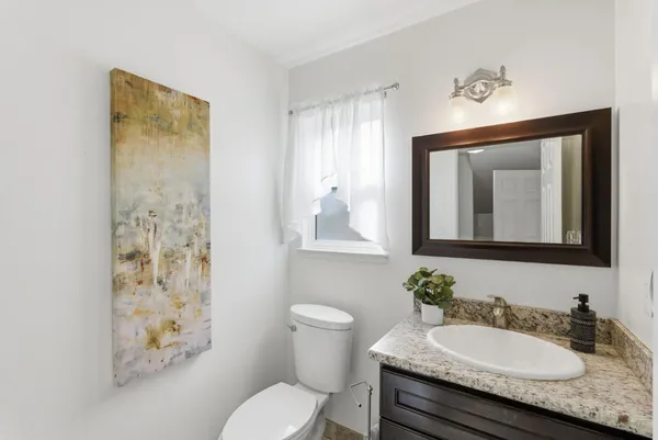 a bathroom with a granite countertop sink toilet and mirror