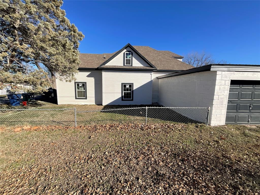 207 College Street Chico, TX 76431 - Photo 4 of 20 View of side of home with a fenced backyard, a garage, and a shingled roof