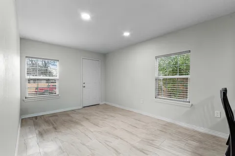 a view of an empty room with wooden floor and a window