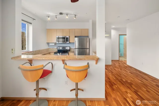 a kitchen with stainless steel appliances granite countertop a refrigerator a stove and a sink with large countertops