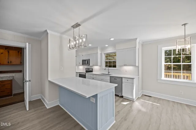 a large white kitchen with cabinets a sink and a stove