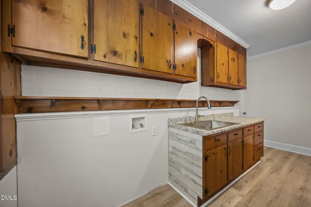 a utility room with stainless steel appliances granite countertop a sink and a cabinets
