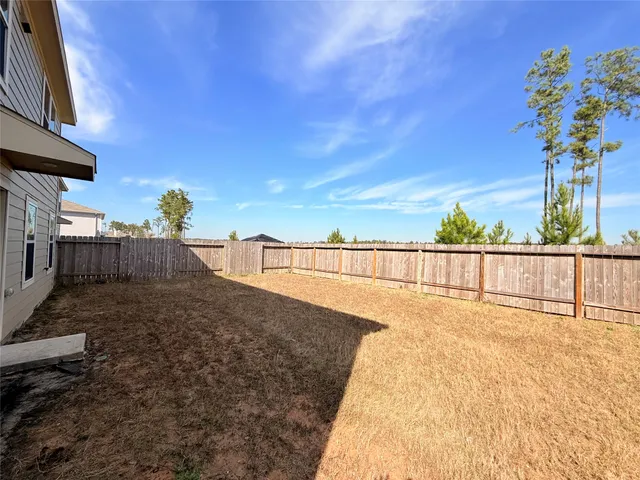 a view of a house with backyard and wooden fence