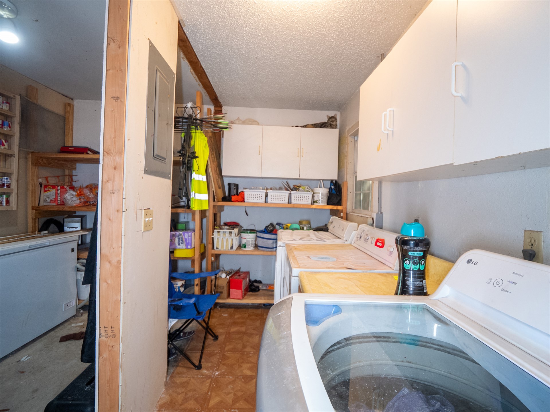 1599 North 4010 Road Boswell, OK 74727 - Photo 47 of 57 Utility space featuring a washer and dryer, upper cabinetry, open shelving, and a wall-mounted electrical panel