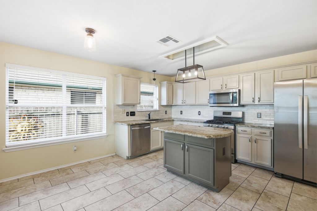 3201 Mocha Trail Austin, TX 78728 - Photo 11 of 26 a kitchen with stainless steel appliances granite countertop a stove a sink dishwasher a refrigerator and white cabinets with wooden floor
